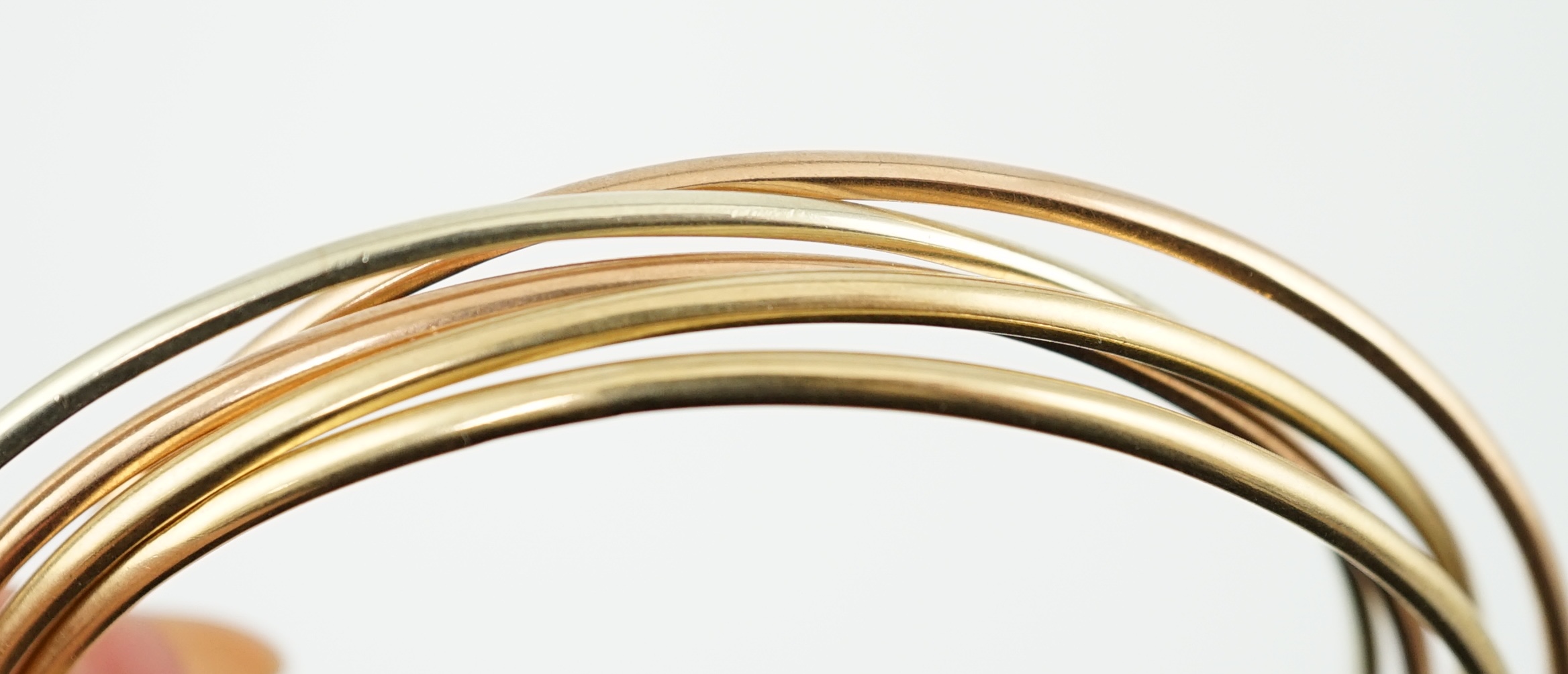 A set of five modern three colour 9ct gold inter-looping bangles